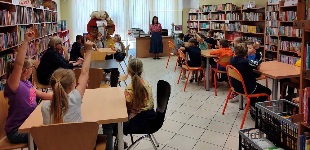 Uczniowie uczestniczący w lekcji bibliotecznej w wypożyczalni dla dzieci
