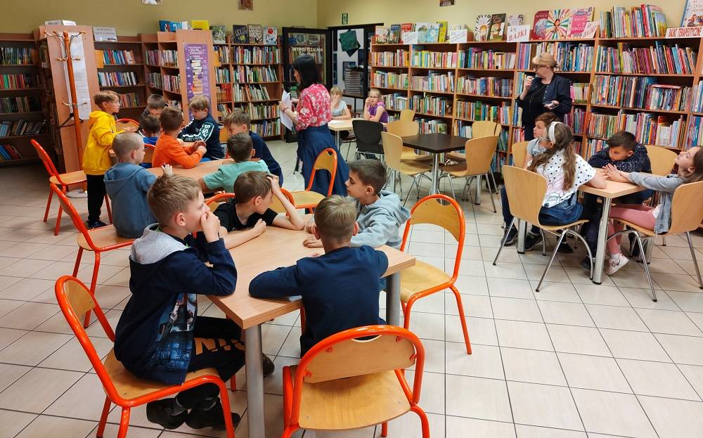 Uczniowie uczestniczący w lekcji bibliotecznej w wypożyczalni dla dzieci