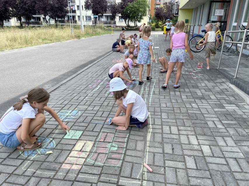 Dzieci rysują kredą po chodniku.