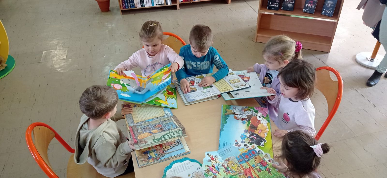 Dzieci przy stoliku przeglądają książki